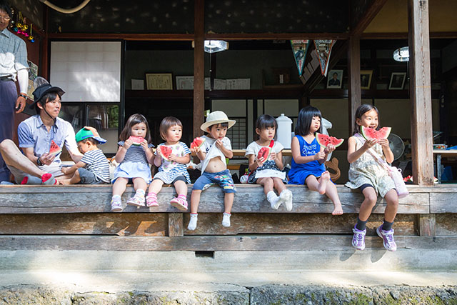 縁側に並んでスイカを食べている子供達