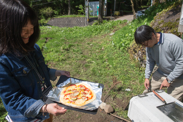 焼けたピザを見せる