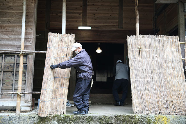 玄関の雪囲いをかたづけている。