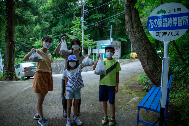 バス停でお土産を見せる家族連れ